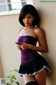 A woman in a purple top and black skirt holding a cell phone.