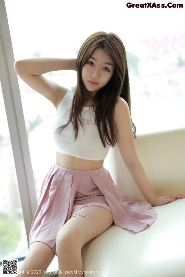 A woman sitting on top of a white couch next to a window.