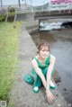 A woman in a green dress sitting on the ground.