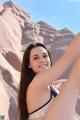 A woman in a black and white bikini posing in the desert.