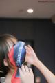 A woman putting a red and blue bandana on her face.