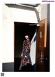 A woman standing in front of a door wearing a floral dress.