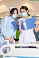 Two nurses wearing face masks standing next to a hospital bed.