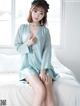 A woman sitting on a bed wearing a blue robe.