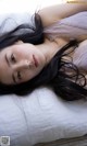 A woman laying on top of a bed with long black hair.