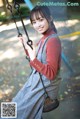 A woman sitting on a swing in a park.