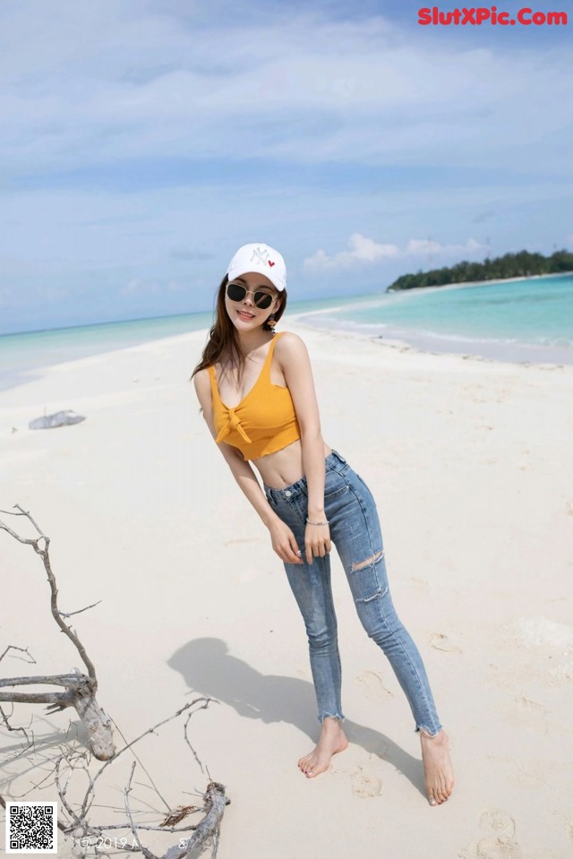 A woman standing on a sandy beach next to the ocean.